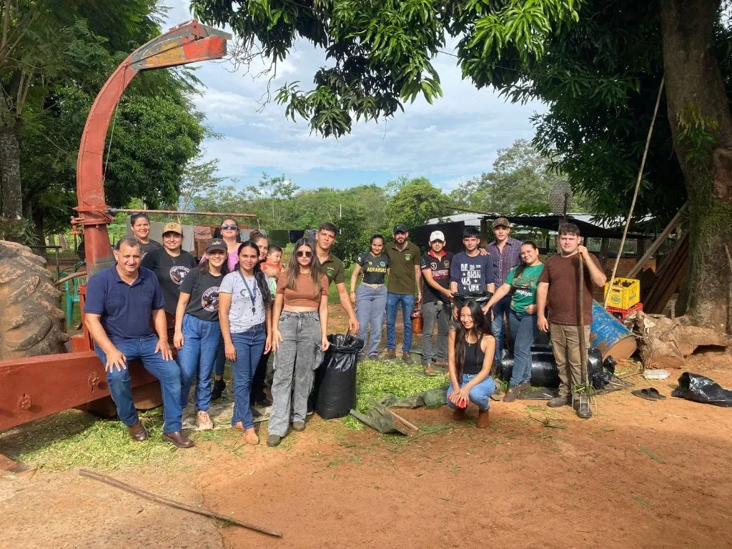 Grupo de estudiantes junto a maquinaria agrícola en el Campo Experimental